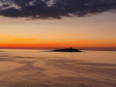 a sunset over the ocean with a boat in the water at CASETTA PONENTE in Isola delle Femmine