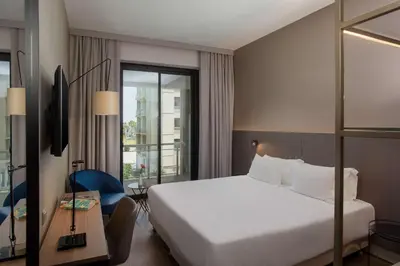 a hotel room with a white bed and a window at NH Palermo in Palermo