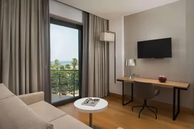 a room with a couch and a desk and a window at NH Palermo in Palermo