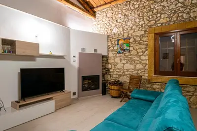 a living room with a blue couch and a television at Scialari Country House in Castellammare del Golfo