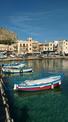 three boats are docked in the water in a harbor at Splendid Hotel La Torre in Mondello