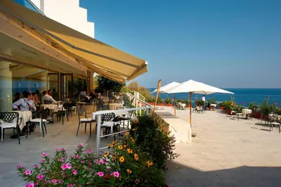a patio with tables and chairs and an umbrella at Splendid Hotel La Torre in Mondello