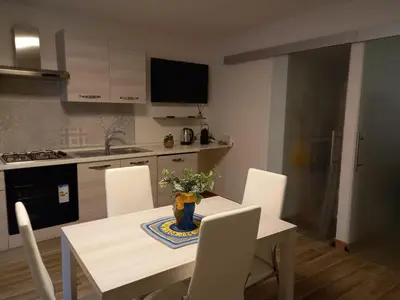 a kitchen with a table with white chairs and a kitchen with a sink at Casa dei Tre Re in Palermo