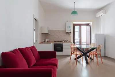 a living room with a red couch and a table at Quattro Canti by DomuSicily in Palermo