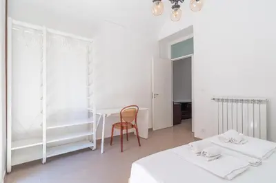 a white room with two beds and a table at Quattro Canti by DomuSicily in Palermo
