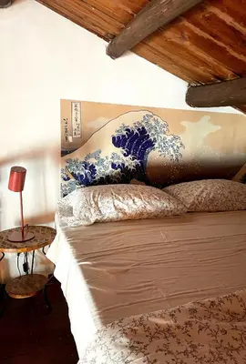 a bed with a large blue and white painting on the wall at Loft Aragonese in Palermo