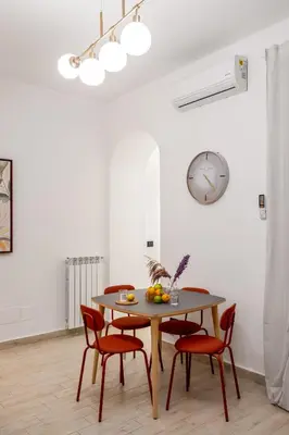 a dining room table with chairs and a clock on the wall at Open Sicily Residence - Central Apartments Near Quattro Canti in Palermo