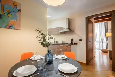 a dining room table with chairs and a kitchen at Open Sicily Residence - Central Apartments Near Quattro Canti in Palermo