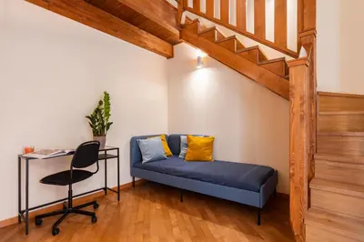 a blue couch in a room with a desk and stairs at Open Sicily Residence - Central Apartments Near Quattro Canti in Palermo
