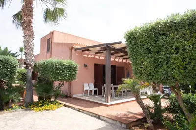 a house with a patio with a table and chairs at Villa Morici con ampio giardino in San Vito lo Capo