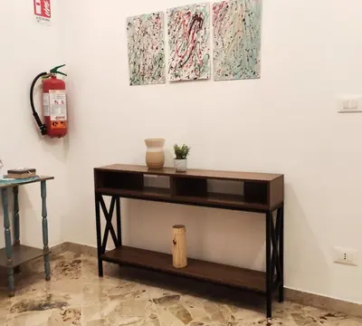 a console table in a living room with paintings on the wall at Amunì rooms and suite LT in Palermo