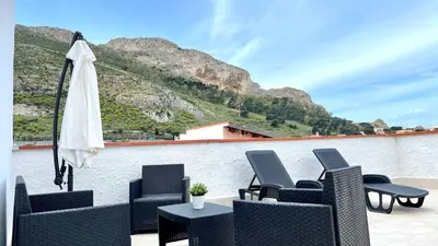 a group of chairs and an umbrella on a patio at La Casetta sul Golfo in Sferracavallo