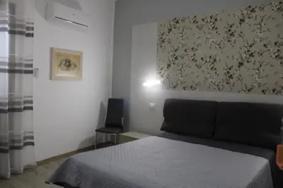 a bedroom with a bed and two chairs and a refrigerator at Terrazza Solemar -four rooms in Castellammare del Golfo