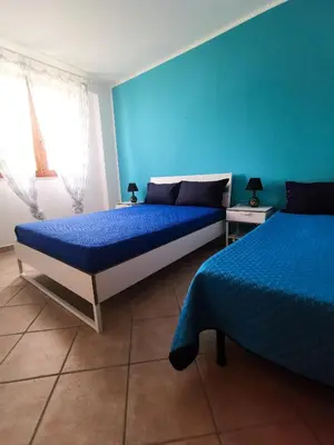 a bedroom with two beds and a blue wall at L'oasi nello Zingaro in Scopello