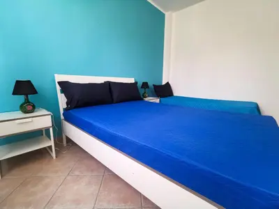 a blue and white bedroom with a bed and a nightstand at L'oasi nello Zingaro in Scopello