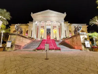 a large building with a staircase with red flowers at Guest House Palermo Massimo 23 in Palermo