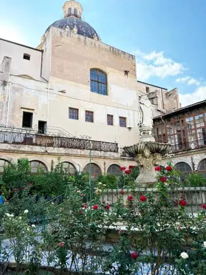 a building with a fountain and flowers in front of it at Palermo Centro - I Pastelli di Van Gogh in Palermo