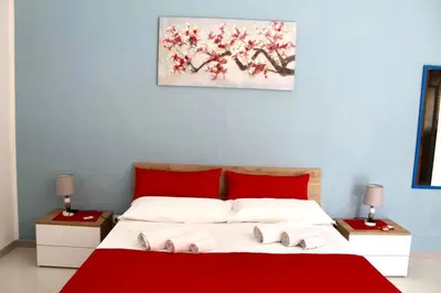 a bedroom with a red and white bed with two tables at B&B La CYCAS in San Vito lo Capo
