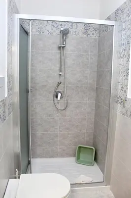 a bathroom with a shower with a toilet and a green stool at B&B La CYCAS in San Vito lo Capo