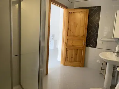 a bathroom with a wooden door and a sink at B&B La CYCAS in San Vito lo Capo