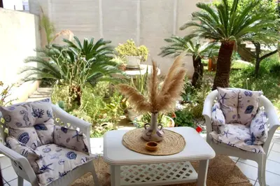 a patio with two chairs and a table and palm trees at B&B La CYCAS in San Vito lo Capo