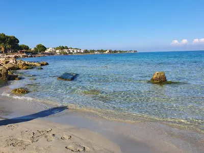 a beach with rocks in the water on a clear day at Airport Home TUREI & BRINGO Car Rental in Cinisi
