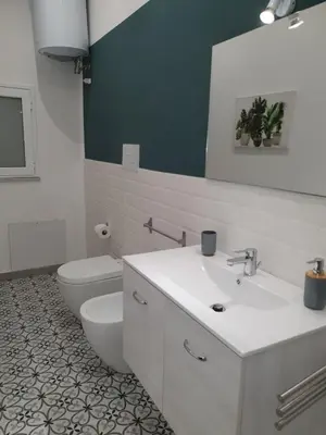 a bathroom with a white sink and a toilet at Airport Home TUREI & BRINGO Car Rental in Cinisi