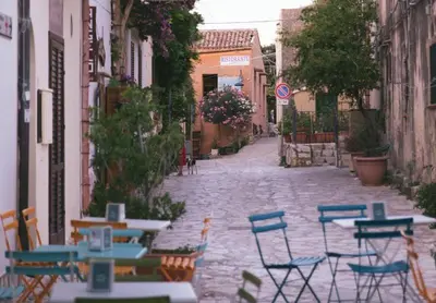an alley with tables and chairs on a street at La casa nel Borgo in Scopello