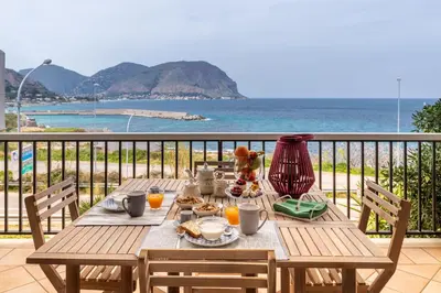 a table with food and a view of the ocean at Il Mare in una Stanza by DomuSicily in Mondello