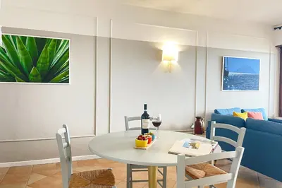 a living room with a table and a blue couch at Il Mare in una Stanza by DomuSicily in Mondello