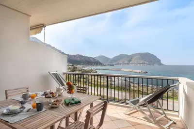 a table on a balcony with a view of the ocean at Mondello in Terrazza by DomuSicily in Mondello
