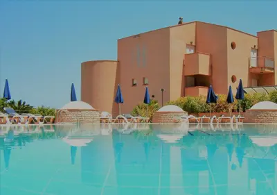 a swimming pool with chairs and umbrellas in front of a building at Addaura Village e Congressi in Mondello