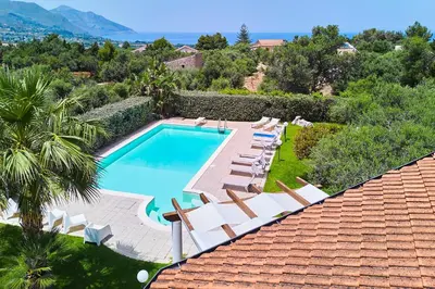 a swimming pool with lounge chairs and a resort at Villa New Charme in Castellammare del Golfo