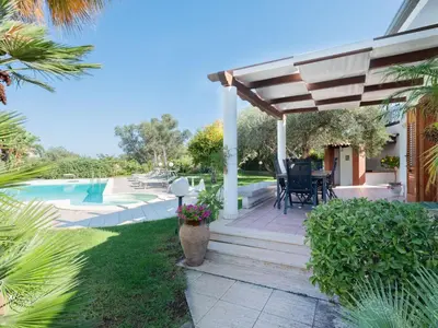 a patio with a table and chairs under a pergola at Villa New Charme in Castellammare del Golfo