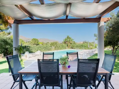 a wooden table and chairs on a patio at Villa New Charme in Castellammare del Golfo