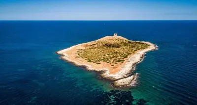 an island in the ocean with a lighthouse on it at L'isola di Fimi in Isola delle Femmine