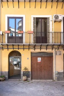 a yellow building with a wooden door and a balcony at Casa Meli dietro Piazza San Domenico by Wonderful Italy in Palermo
