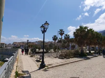 a street light on a sidewalk with palm trees at La Casetta di Giò! in Castellammare del Golfo