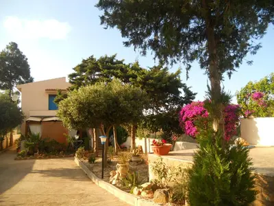 a garden with trees and flowers in front of a house at CASE PUNTA MONACO by Trerose Properties con wi-fi e posto auto privato gratuito in San Vito lo Capo