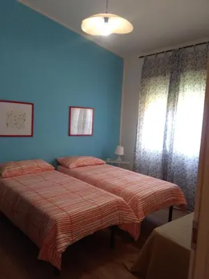 two beds in a bedroom with blue walls and a window at CASE PUNTA MONACO by Trerose Properties con wi-fi e posto auto privato gratuito in San Vito lo Capo