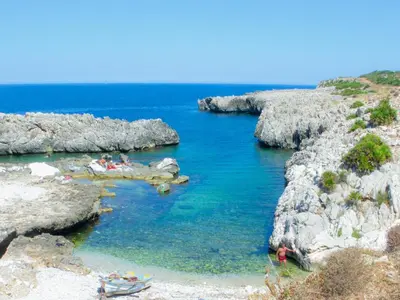 a group of people in the water near some rocks at CASE PUNTA MONACO by Trerose Properties con wi-fi e posto auto privato gratuito in San Vito lo Capo