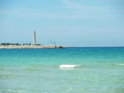 a body of water with a lighthouse in the background at VILLETTA MAGNOLIE by Trerose Properties - Villetta indipendente con wi-fi e posto auto gratuito in San Vito lo Capo