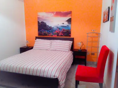 a bedroom with a bed and a red chair at VILLETTA MAGNOLIE by Trerose Properties - Villetta indipendente con wi-fi e posto auto gratuito in San Vito lo Capo