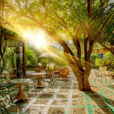 a patio with tables and chairs under a tree at Magaggiari Hotel Resort in Cinisi