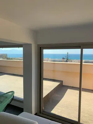 a living room with a view of the ocean seen through windows at Appartamento in Villa con idromassaggio in Balestrate