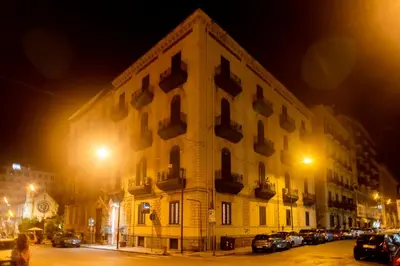 a large building with cars parked in front of it at night at Hotel Tonic in Palermo