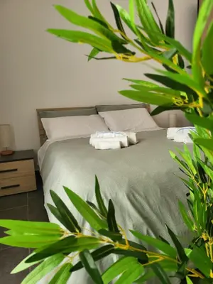 a bedroom with a bed with green sheets and plants at Giovenchi’s Apartment in Palermo