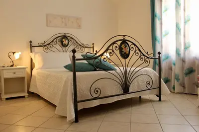 a bedroom with a bed with a white comforter at Desy Appartamenti in San Vito lo Capo