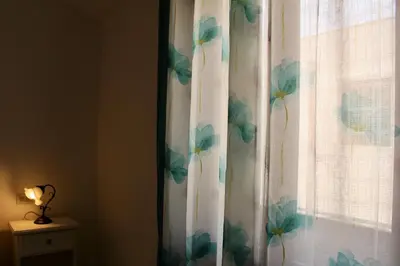 a curtain with a flower pattern on a window at Desy Appartamenti in San Vito lo Capo