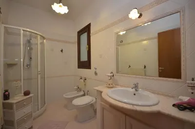 a bathroom with a sink and a toilet and a mirror at Desy Appartamenti in San Vito lo Capo